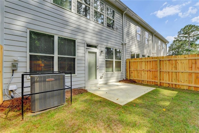 rear view of property with a yard, a patio area, fence, and central AC unit