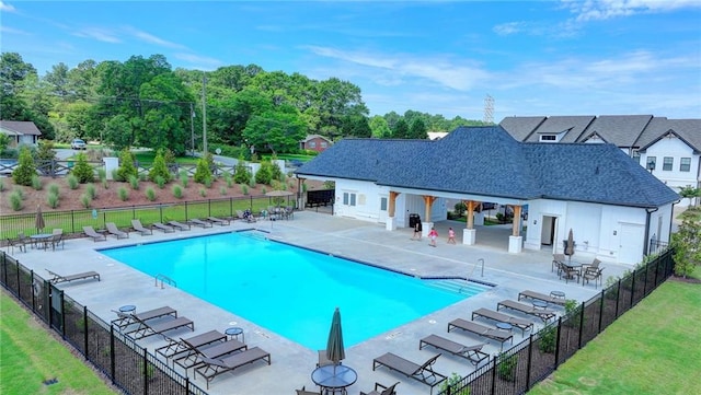 community pool with a patio area, fence, and a yard