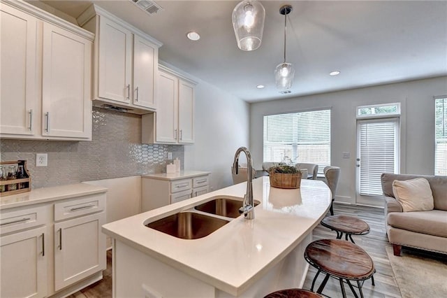 kitchen with a breakfast bar, visible vents, decorative backsplash, open floor plan, and a sink