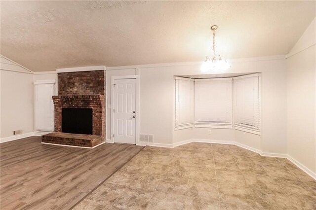 unfurnished living room with an inviting chandelier, a textured ceiling, wood-type flooring, a brick fireplace, and vaulted ceiling