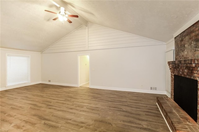 bonus room featuring a brick fireplace, vaulted ceiling with beams, hardwood / wood-style flooring, and ceiling fan