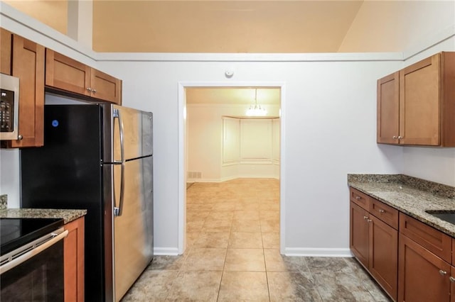 kitchen with light stone counters, stainless steel appliances, lofted ceiling, and light tile patterned floors