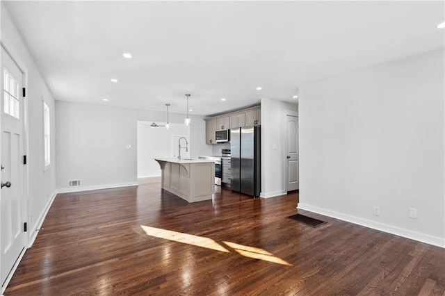 kitchen featuring light countertops, appliances with stainless steel finishes, a breakfast bar area, and visible vents