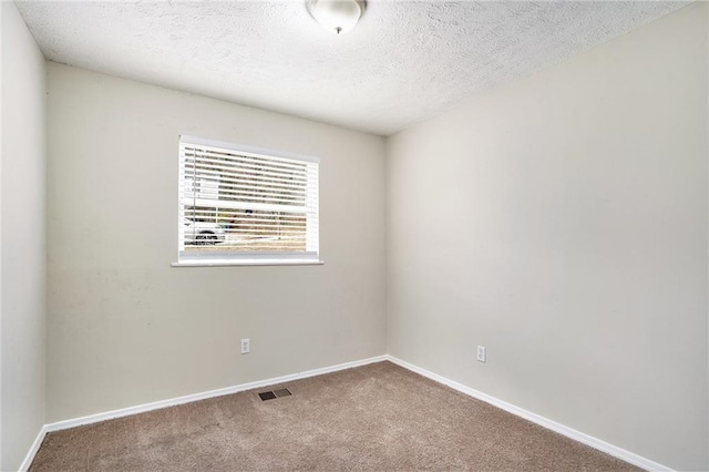 carpeted empty room featuring a textured ceiling