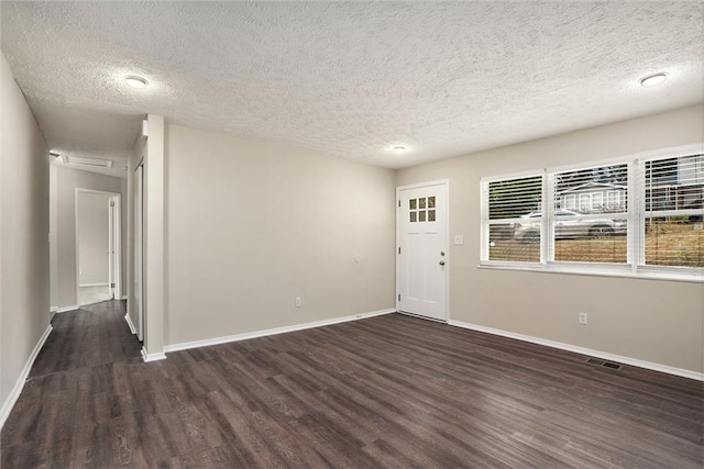 spare room featuring dark hardwood / wood-style flooring and a textured ceiling