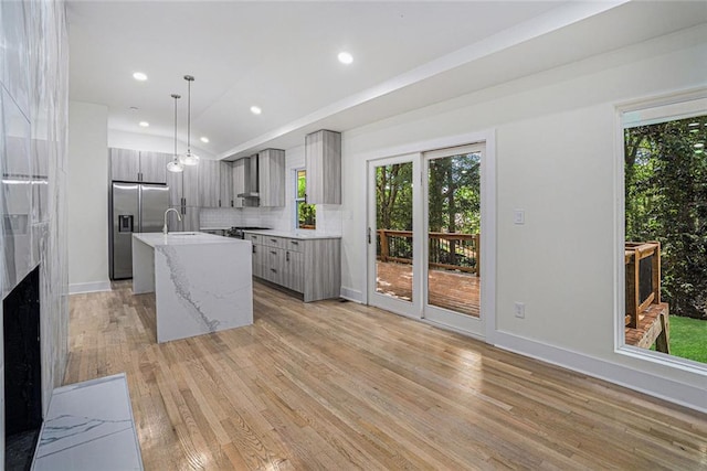 kitchen featuring modern cabinets, plenty of natural light, stainless steel fridge with ice dispenser, and light wood-style floors