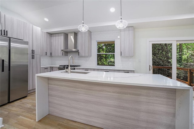 kitchen with modern cabinets, light wood-style flooring, stainless steel refrigerator with ice dispenser, tasteful backsplash, and wall chimney exhaust hood