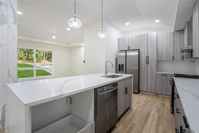 kitchen with a center island with sink, a sink, light wood-style floors, appliances with stainless steel finishes, and modern cabinets