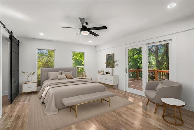 bedroom featuring baseboards, light wood-type flooring, a barn door, recessed lighting, and access to outside