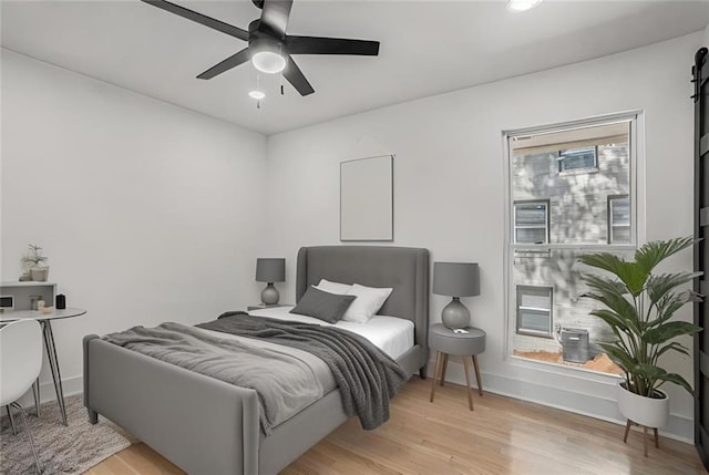 bedroom featuring light wood-style flooring, a ceiling fan, and baseboards