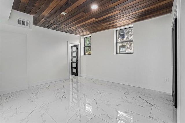 spare room featuring visible vents, baseboards, marble finish floor, and wood ceiling