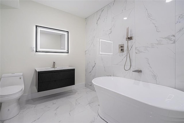 full bathroom with a freestanding bath, vanity, toilet, marble finish floor, and stone wall