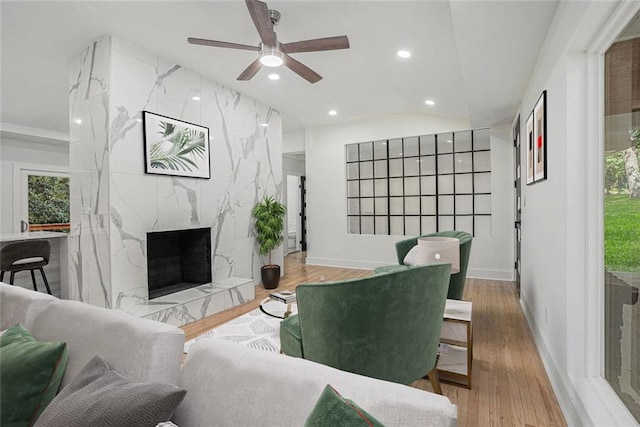 living area featuring wood finished floors, baseboards, a premium fireplace, recessed lighting, and ceiling fan