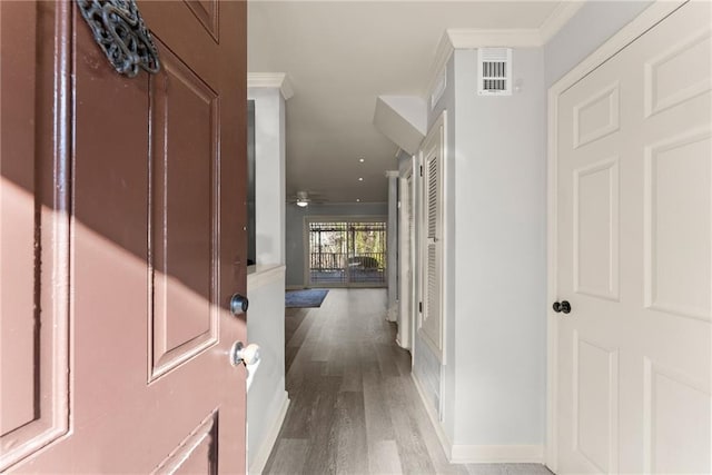 interior space with ceiling fan, ornamental molding, and light wood-type flooring