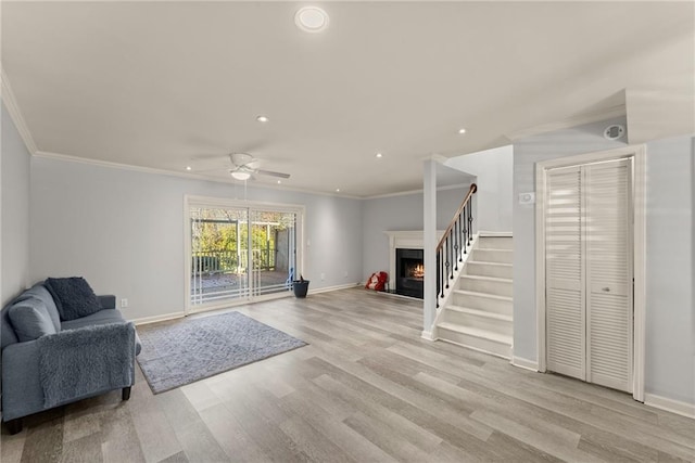 living room with ornamental molding, ceiling fan, and light hardwood / wood-style flooring