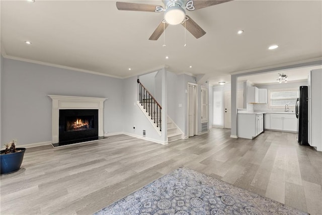 living room featuring crown molding, ceiling fan, sink, and light wood-type flooring