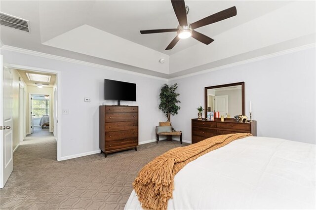 carpeted bedroom featuring ceiling fan, crown molding, and a tray ceiling