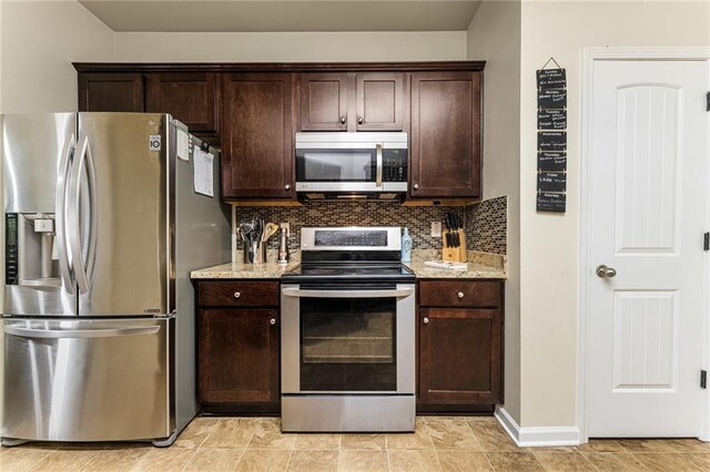 kitchen with light stone countertops, appliances with stainless steel finishes, dark brown cabinetry, and tasteful backsplash