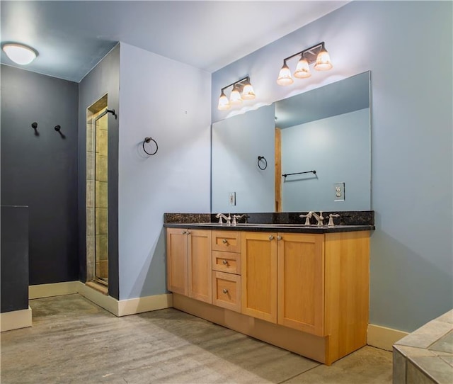 full bath featuring double vanity, baseboards, a stall shower, and a sink