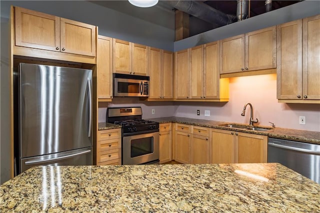 kitchen featuring a sink, light stone countertops, light brown cabinets, and stainless steel appliances