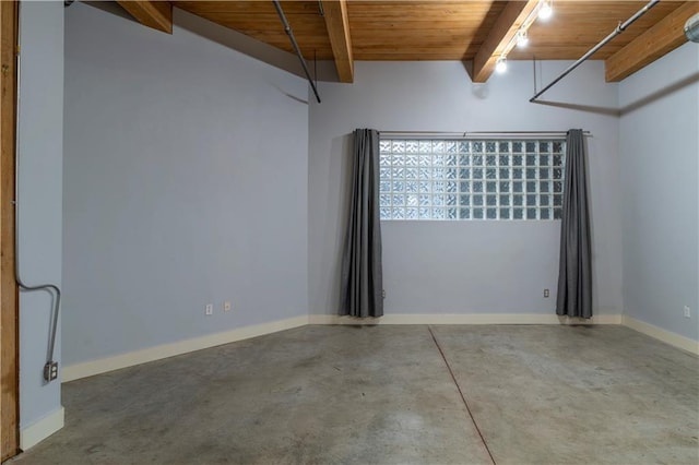 empty room with baseboards, beam ceiling, concrete flooring, and wood ceiling