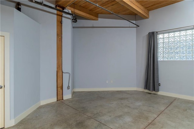 unfurnished room with beamed ceiling, baseboards, concrete floors, and wooden ceiling