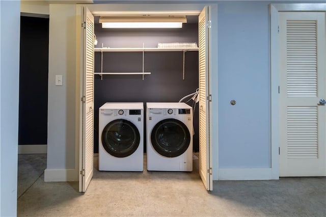 laundry area with laundry area, washer and dryer, and baseboards