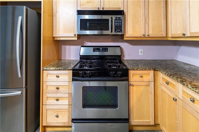 kitchen featuring dark stone countertops, light brown cabinetry, and stainless steel appliances