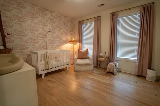 1122 Rice St NW, Atlanta, GA 30318 - bedroom with wallpapered walls, wood finished floors, a crib, and baseboards