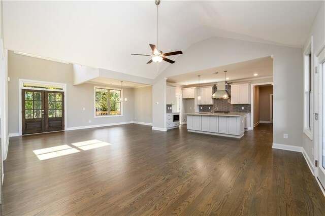 unfurnished living room featuring dark wood-type flooring, high vaulted ceiling, ceiling fan, french doors, and sink