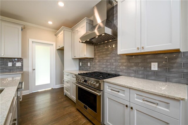 kitchen with tasteful backsplash, dark wood-type flooring, wall chimney range hood, white cabinetry, and high end stove