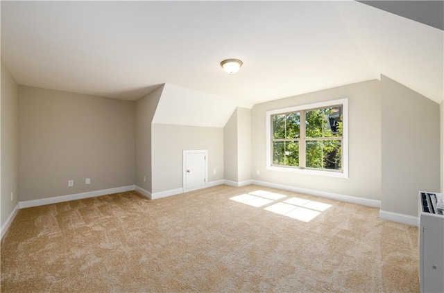 additional living space featuring lofted ceiling and light colored carpet