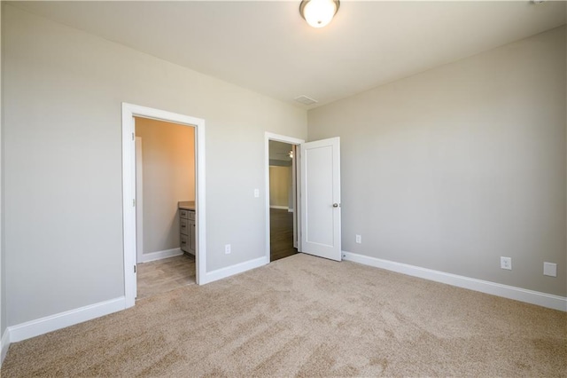 unfurnished bedroom with light colored carpet and ensuite bath