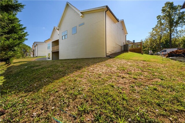 view of side of property with cooling unit, a wooden deck, and a lawn