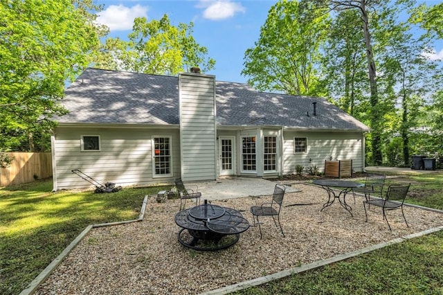 rear view of property featuring a chimney, fence, an outdoor fire pit, a yard, and a patio
