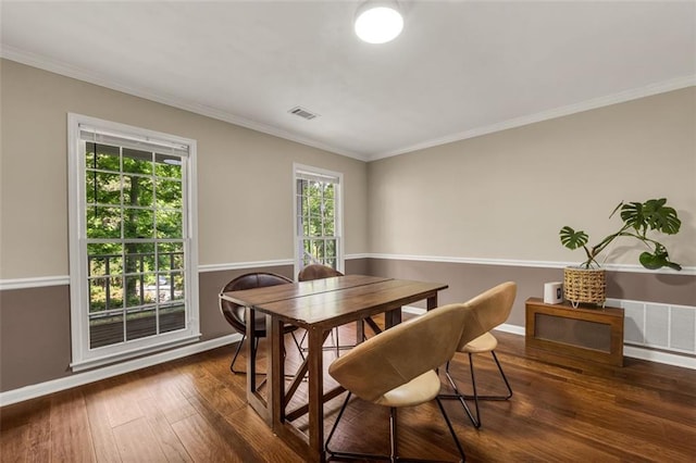 dining room with wood-type flooring, baseboards, visible vents, and crown molding