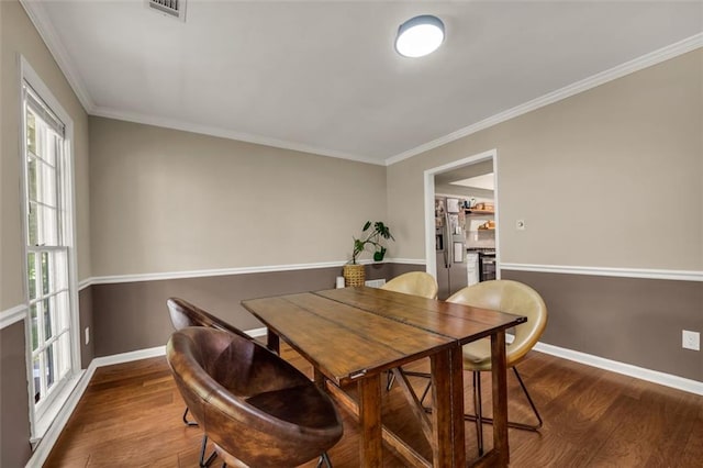dining area featuring crown molding, baseboards, wood finished floors, and a wealth of natural light