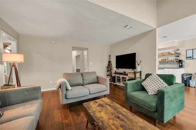 living room with baseboards, visible vents, and wood finished floors