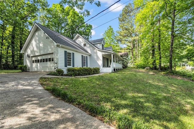 view of side of home featuring a lawn, covered porch, an attached garage, and driveway