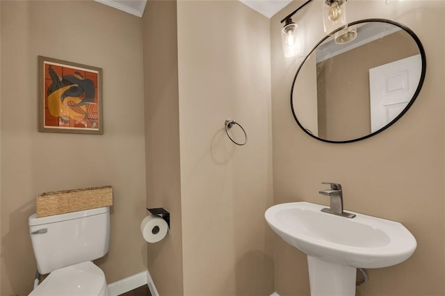 half bath featuring toilet, baseboards, and a sink