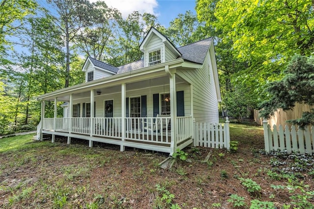 view of front of property featuring roof with shingles, fence, and covered porch