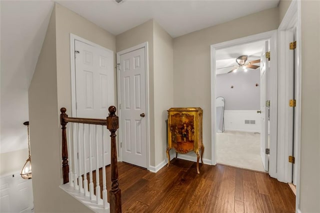 hall with baseboards, an upstairs landing, dark wood-style floors, and visible vents