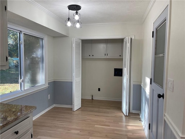 laundry area with light hardwood / wood-style floors, plenty of natural light, and ornamental molding