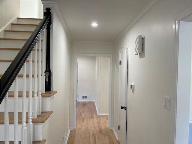 hallway featuring crown molding and light hardwood / wood-style flooring