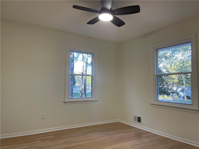 empty room featuring ceiling fan, light wood-type flooring, and a wealth of natural light