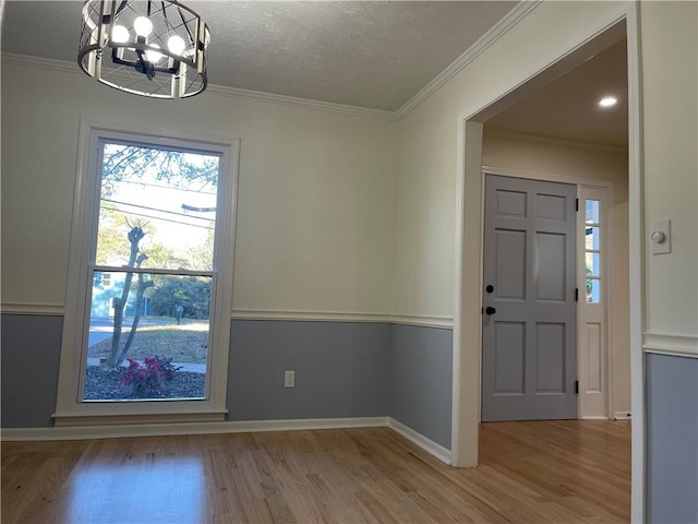 interior space featuring a notable chandelier, light hardwood / wood-style floors, ornamental molding, and a textured ceiling