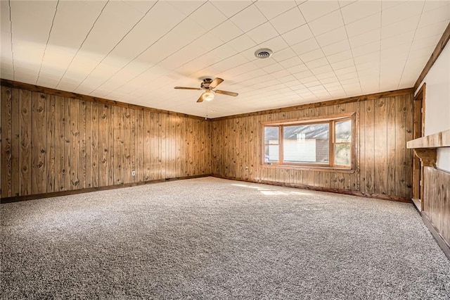 empty room featuring baseboards, visible vents, carpet floors, ceiling fan, and wood walls