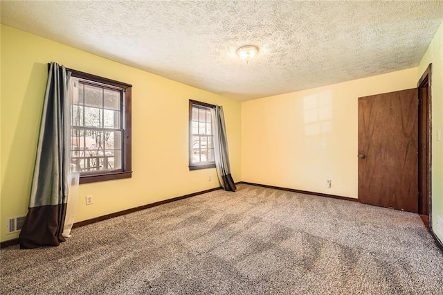 carpeted empty room with visible vents, baseboards, and a textured ceiling