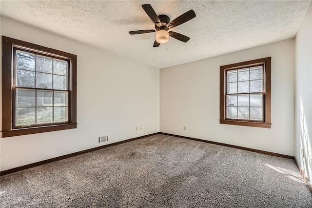 spare room featuring visible vents, carpet floors, a textured ceiling, and baseboards