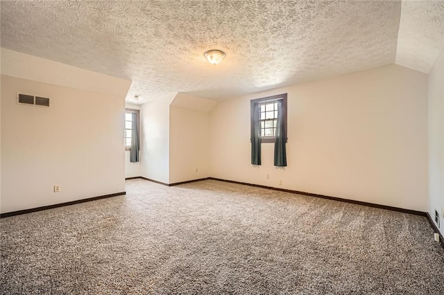 unfurnished room with visible vents, carpet floors, plenty of natural light, and lofted ceiling